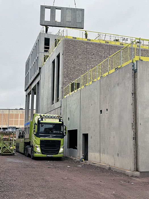 Byggnation av det nya Jungmannen-hotellet i Kalmar hamn med lyft av betongelement och lastbil på arbetsplatsen.